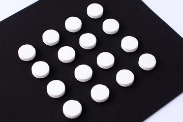 Round white medical pills arranged in square order. Pill splitting.