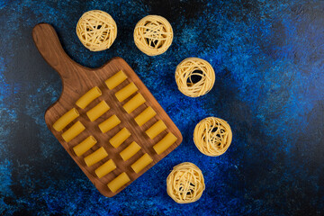 Pastas on a wooden platter on blue background