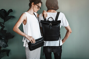 Street style concept. Beautiful girl with a boyfriend presenting designer leather bags. Backpack...