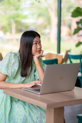 Young business asian woman sitting at cafe working with notebook