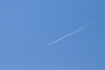 The airplane fast movement with condensation lines on the blue sky