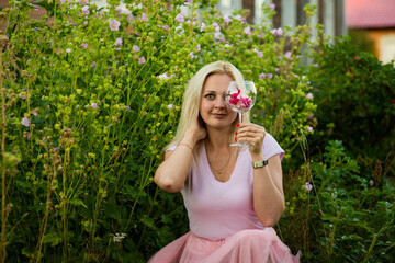 blonde girl with a glass of flowers in summer, selective focus