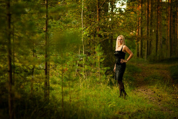 blonde girl in black dress in the woods, selective focus