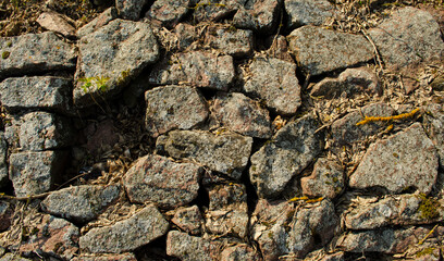 Cobblestone with grass texture stone path road pathway background of paving texture old. Broken paving overgrown with grass. Without one cobblestone