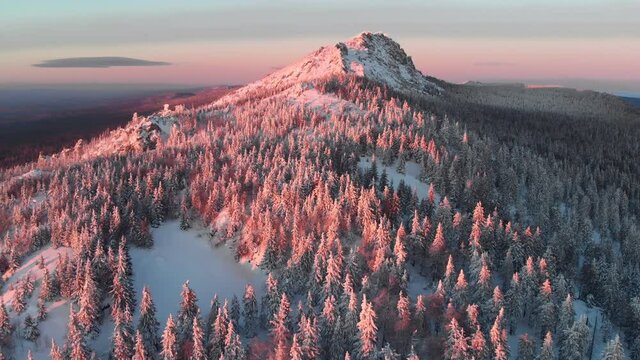beautiful sunset above snow mountains, aerial view. national park Taganay in Russia. scenic winter landscape, nature background. majestic red sunset light on treetops and cliffs.