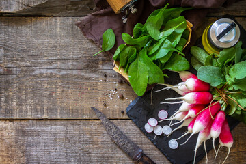 Summer salad ingredients, organic vegetables and olive oil. Raw fresh juicy radish on a rustic table. Top view flat lay background. Copy space.