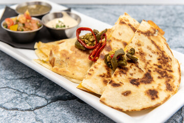 Stuffed quesadilla halves on a plate topped with chopped jalepeno peppers roasted to perfection.