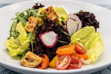 Salad bowl of fresh greens, tomatoes, and croutons full of all the colors.