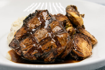 Filet mignon steak glazed in sauce served with roasted brussel sprouts halves on a plate for dinner.