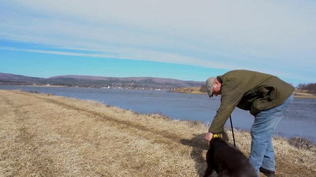 A mature man walking in pain.  A man in his late fifties walking his dog.  