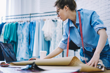 Focused dressmaker browsing laptop working in modern workshop
