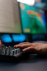 Fototapeta premium Close up of streamer checking mixer buttons for online gamimg championship playing shoother videogames in home studio