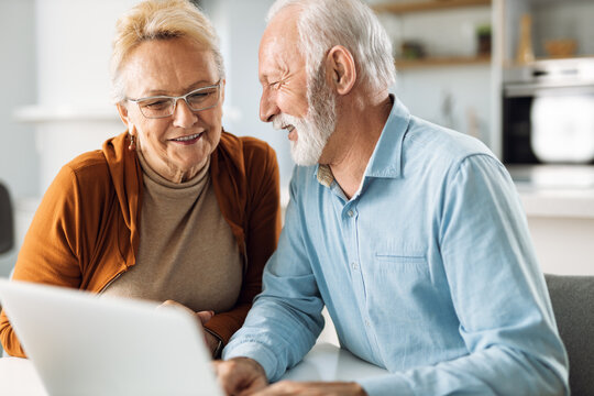 Happy Mature Couple Surfing The Internet On Laptop At Home