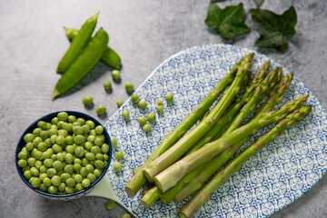 Delicious asparagus with peas on a blue plate and stone background