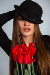 portrait of a beautiful girl in a hat with tulips in hands
