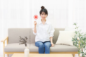 窓際のソファに座ってOKのプラカードを持つ若い女性