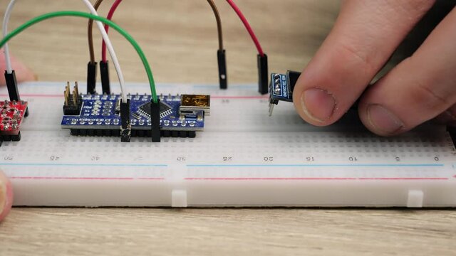 Working with electronics microcircuits on a breadboard, the hand of a white man arranges microcircuits, the concept of working with electrical modules and programming