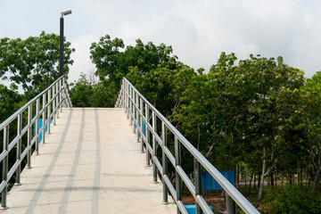 Fototapeta na wymiar An elevated cement bridge with steel handrails for crossing the river inside the park. Landmark at Kodpor Public Park, Rayong ,Thailand.