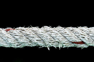 Close-up of white 
Manila Rope taut in a straight lineon isolate black background.