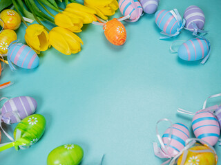 Bouquet of spring yellow tulips and colorful easter eggs on a blue background