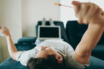 Young Businessman working at home with paper graph and he is stretch lazily on sofa. Business and freelance concept.