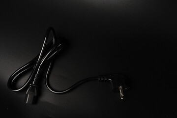 The electric power wire for the PC is black on a black background and a place for text. Dimmed lights.