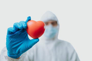 The doctor hold red heart and wearing personal protective equipment or ppe, mask, goggle and suit to protect COVID-19 infection. coronavirus, medical, healthcare concept