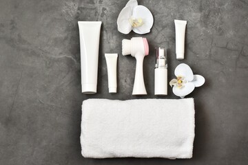White cosmetic tubes, towel with flowers orchid on concrete gray background.  Mock-up bottle for branding and label. Natural organic spa cosmetics concept. 