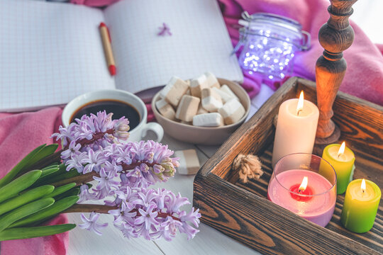 Early spring still life scene. Cup of coffee and marshmallow, opened notebook, pink plaid and candles on windowsill. Cozy Easter, vintage feminine styled photo