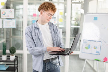 Young male IT specialist using laptop for work at office