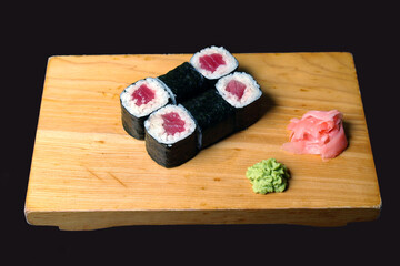 rolls tuna rice wrapped in nori ginger wasabi leaves served on a wooden stand on a dark background useful dietary food