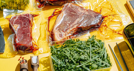 vacuum packed raw beef steaks ready to fry. t-bone steak from marbled beef. meat and vegetables