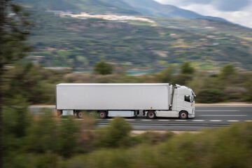 Truck with refrigerated semi-trailer driving fast on the highway with the rest of the image in motion, creating a speed effect.