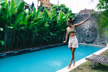 Ethnic woman walking on pool edge in tropical resort