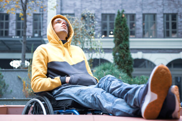 Fototapeta na wymiar Young man in the wheelchair crossing his legs