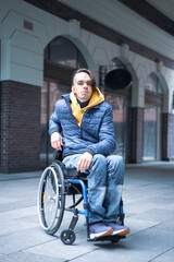 Young man in the wheelchair looking at camera. Front view