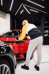 Car detailing - Worker with orbital polisher in auto repair shop. Selective focus.