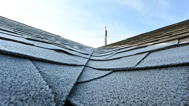 time lapse video of frost melting from a residential shingle roof as the sun rises in the morning