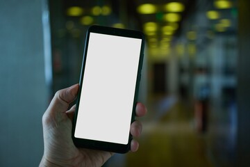Hand holding mobile phone with blank screen in modern office, walking, moving.