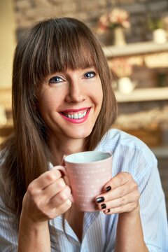 Closeup portrait of happy white woman at home drinking coffee at morning in kitchen.