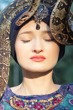 Close up of woman in oriental dress having a snake on her head