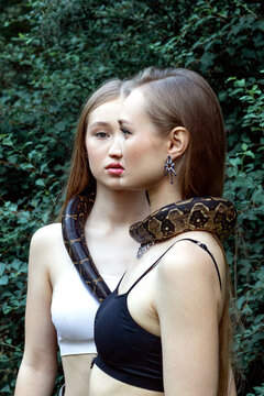 Models standing next to each other having a snake around their necks
