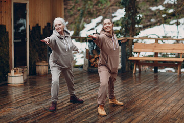Women doing exercises sports and fitness outdoors. Young and senior elderly woman warming up and yoga at glamping. Mother and daughter having zen like modern fitness vacation.