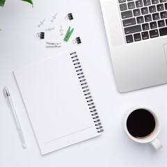 Top view on working space with a white notebook with free space for text in the center. A designer workplace with stationery items and colorful stuff.