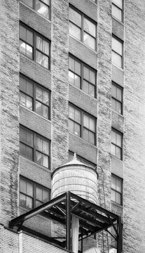 Black and white picture of water tower on a roof of an old building in Manhattan, New York City, USA.