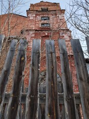 Old brick building behind a wooden fence