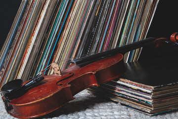 a violin is leaning against a pile of vinyl records