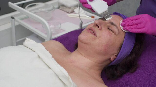 The beautician performs cavitation peeling using an ultrasound device.