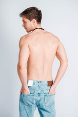 Young muscular man with a naked torso dressed in blue jeans on a white background. Copy, empty space for text