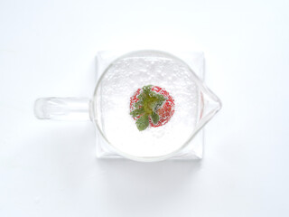 transparent teapot with clear water and red strawberries